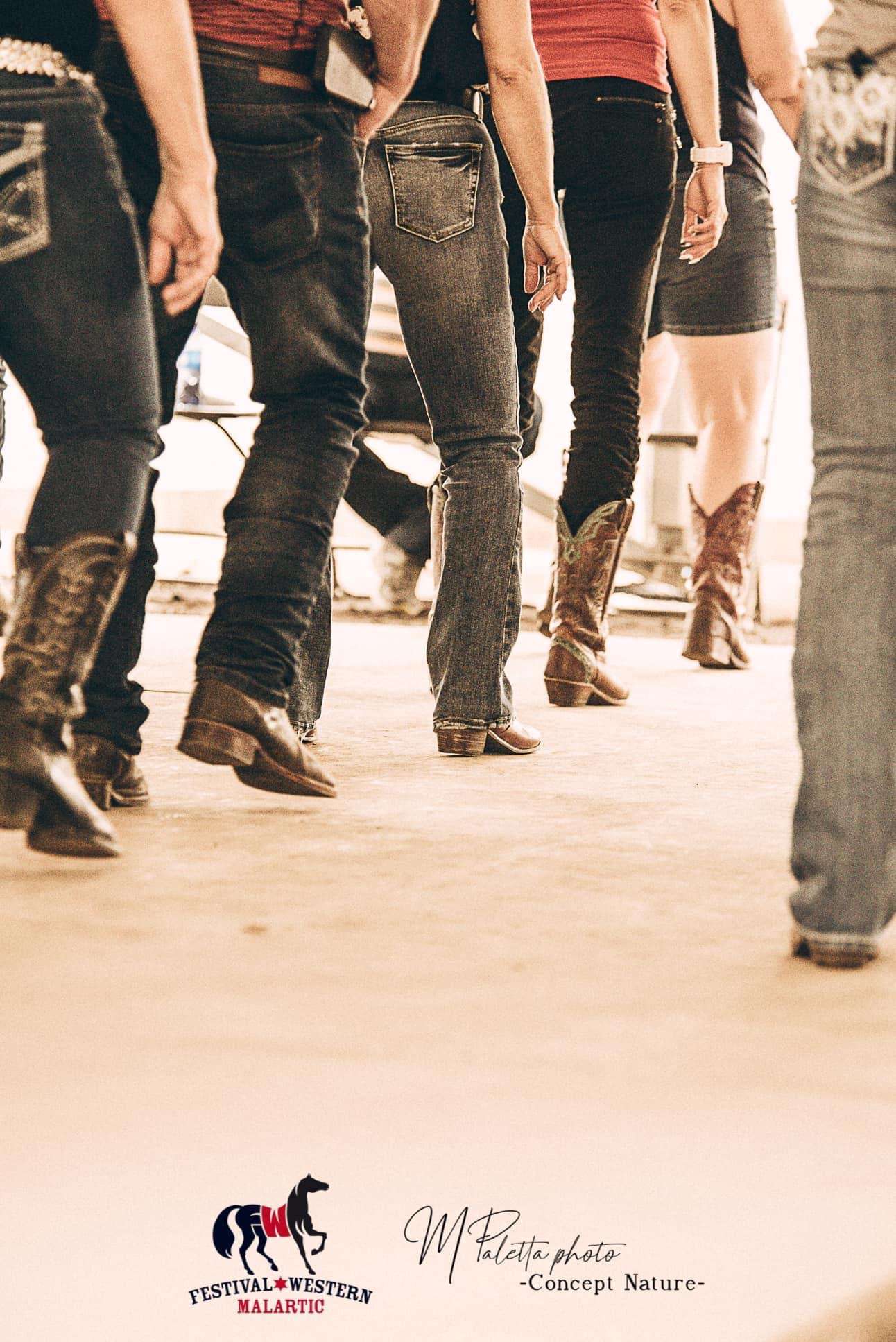 La photo présente le bas de corps de six danseurs. Ils portent tous des bottes de cowboy et font une danse en ligne. 